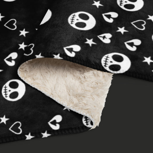 Black sherpa blanket with repeating white skull/ghoul, heart, and star geometric pattern, oversized emo aesthetic throw