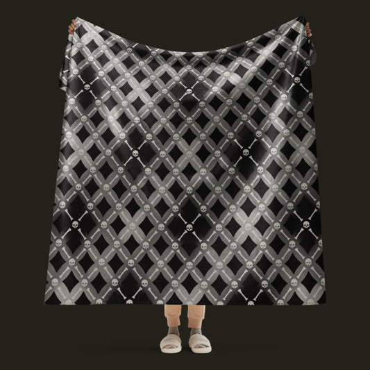 A fleece sherpa blanket with a soft argyle pattern and skulls and bones diagonals