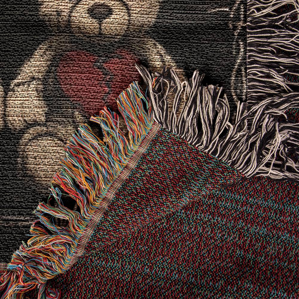 detail of a woven blanket with x-eyed teddy bears on a dark background and surrounded by a frame of barbed wire