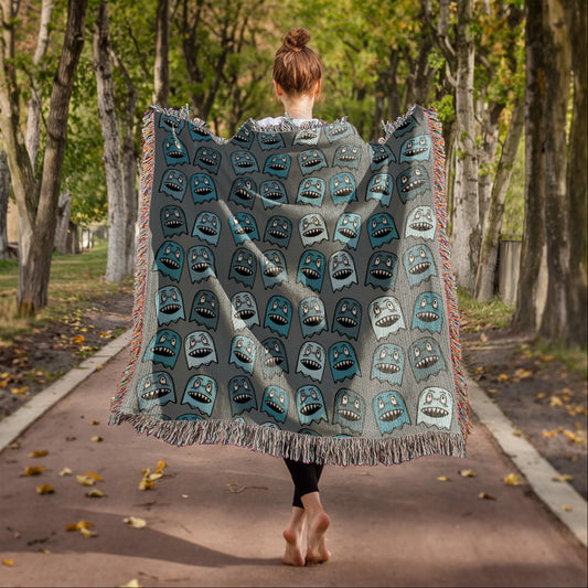 A woven blanket with grinning blue shade goblins on a grey background