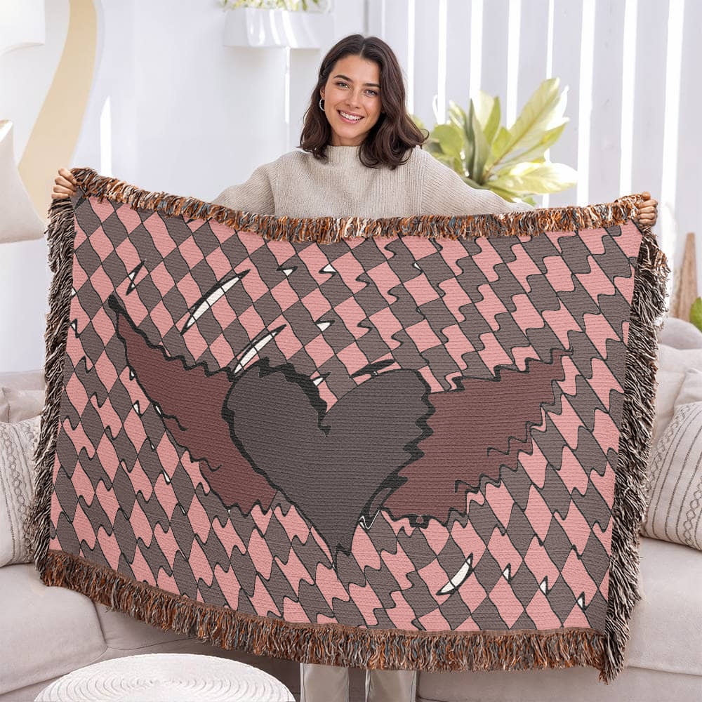 woman holding a woven blanket with a deep red heart with wings on a distorted checkered pattern