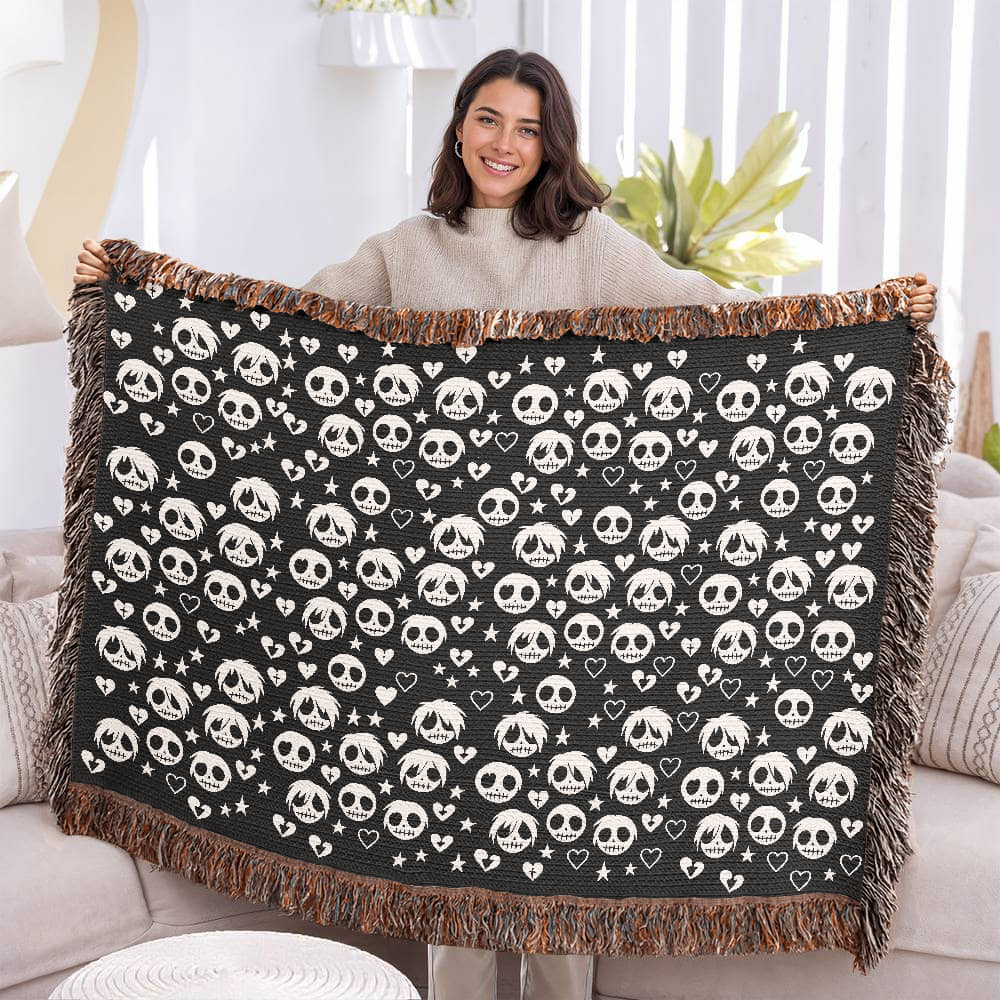 a woven blanket with a pattern of stitch mouthed emo ghouls and broken hearts on a dark background