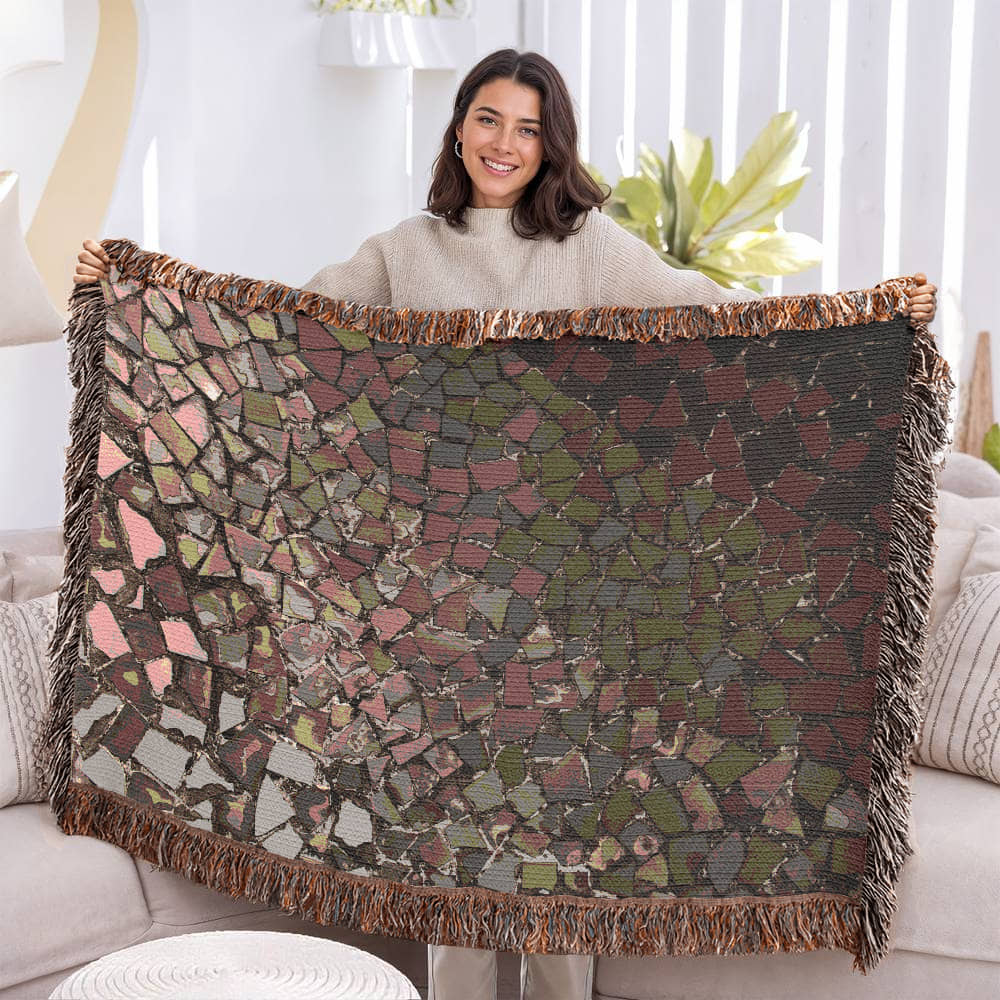 A woven blanket with deep red, black and lighter color shattered mosaic image