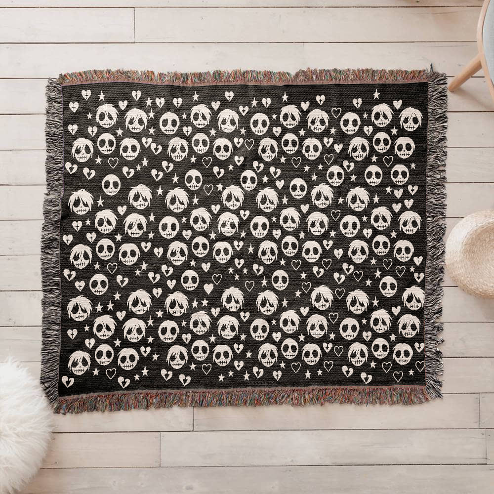 a woven blanket with a pattern of stitch mouthed emo ghouls and broken hearts on a dark background