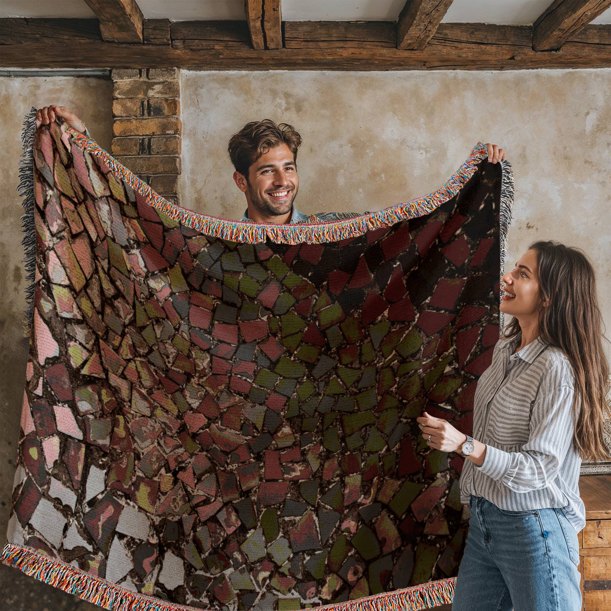 A woven blanket with deep red, black and lighter color shattered mosaic image
