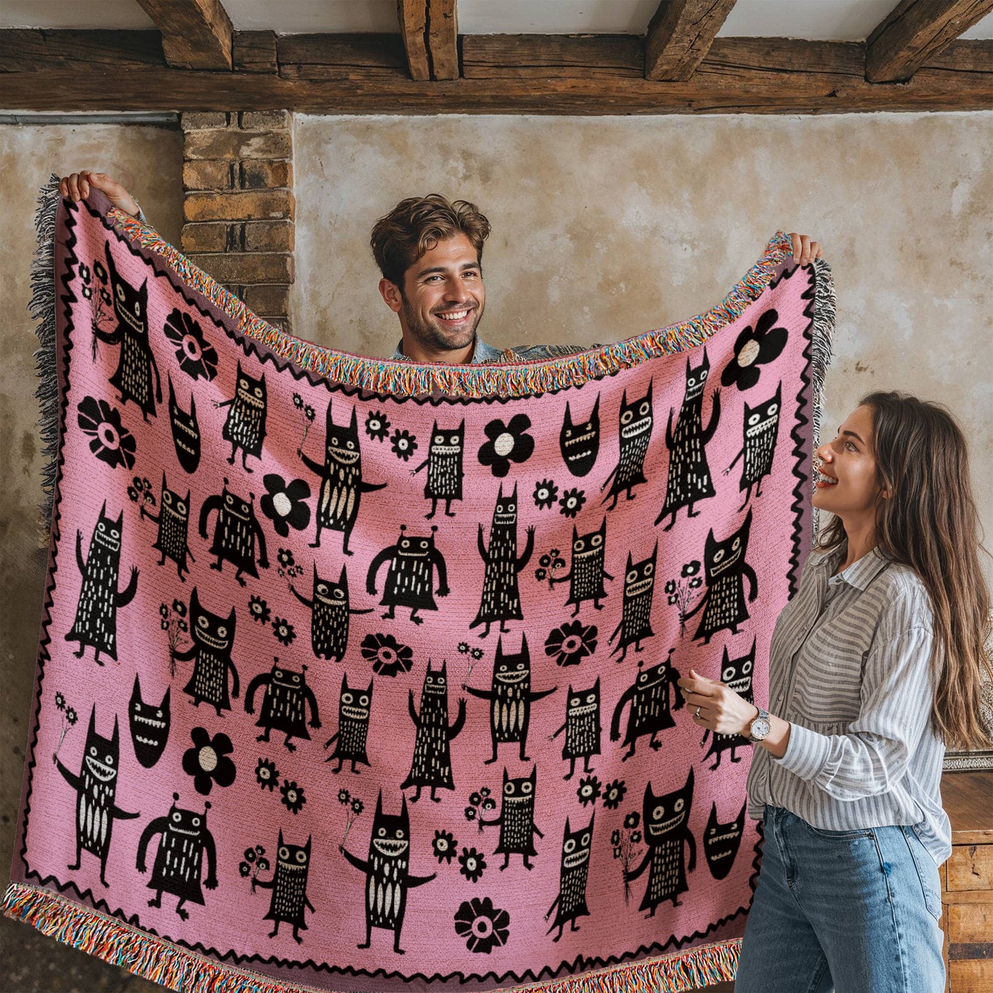 a pink woven blanket featuring grinning goon-goblins and flowers