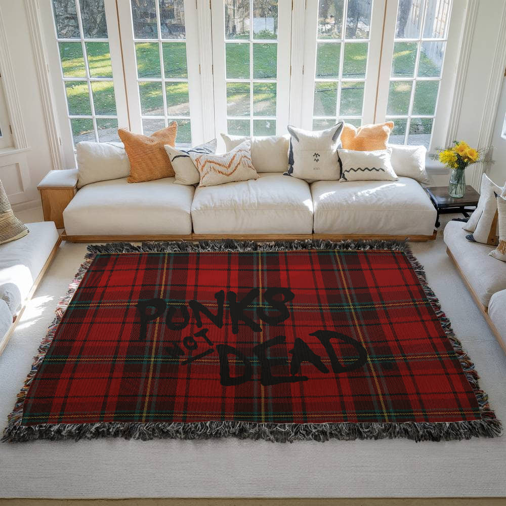 Red plaid woven blanket blanket with text 'Punks Not Dead' on a floor