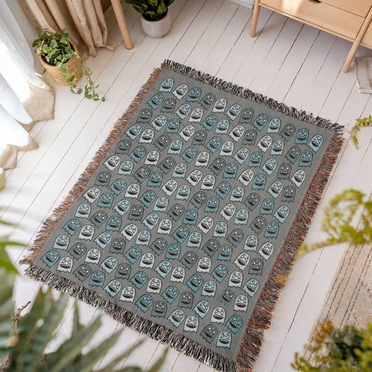 A woven blanket with grinning blue shade goblins on a grey background