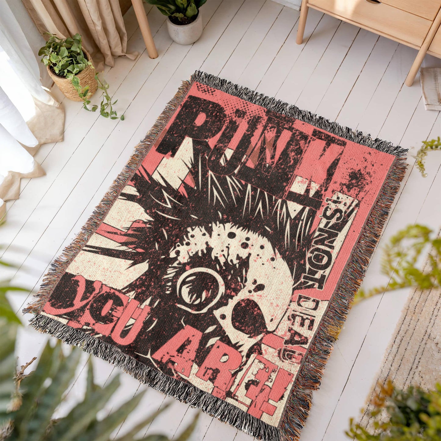 a woven blanket with a punk collage in pink and black, with text and a mohawk skull