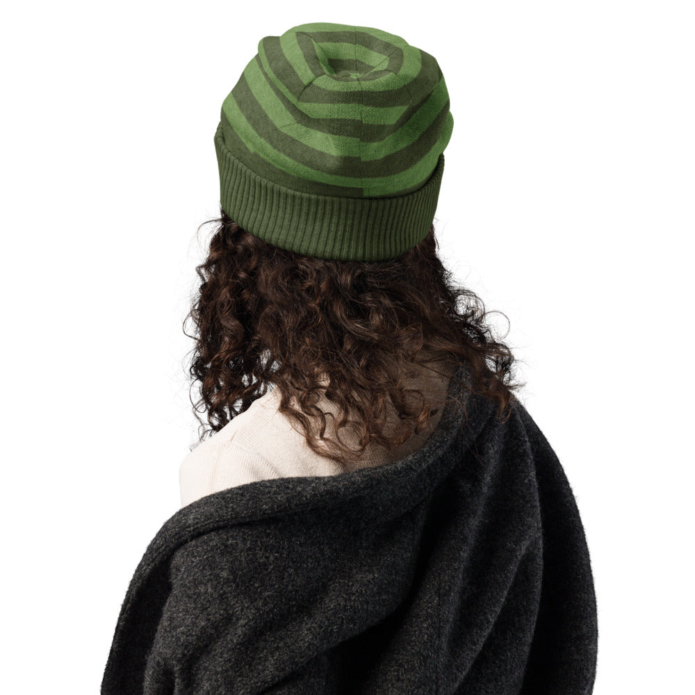 woman wearing a green striped beanie with a black skull and pink x-eyes