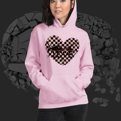 Person wearing a pink hoodie with a pink checkered and distressed heart design against a dark background