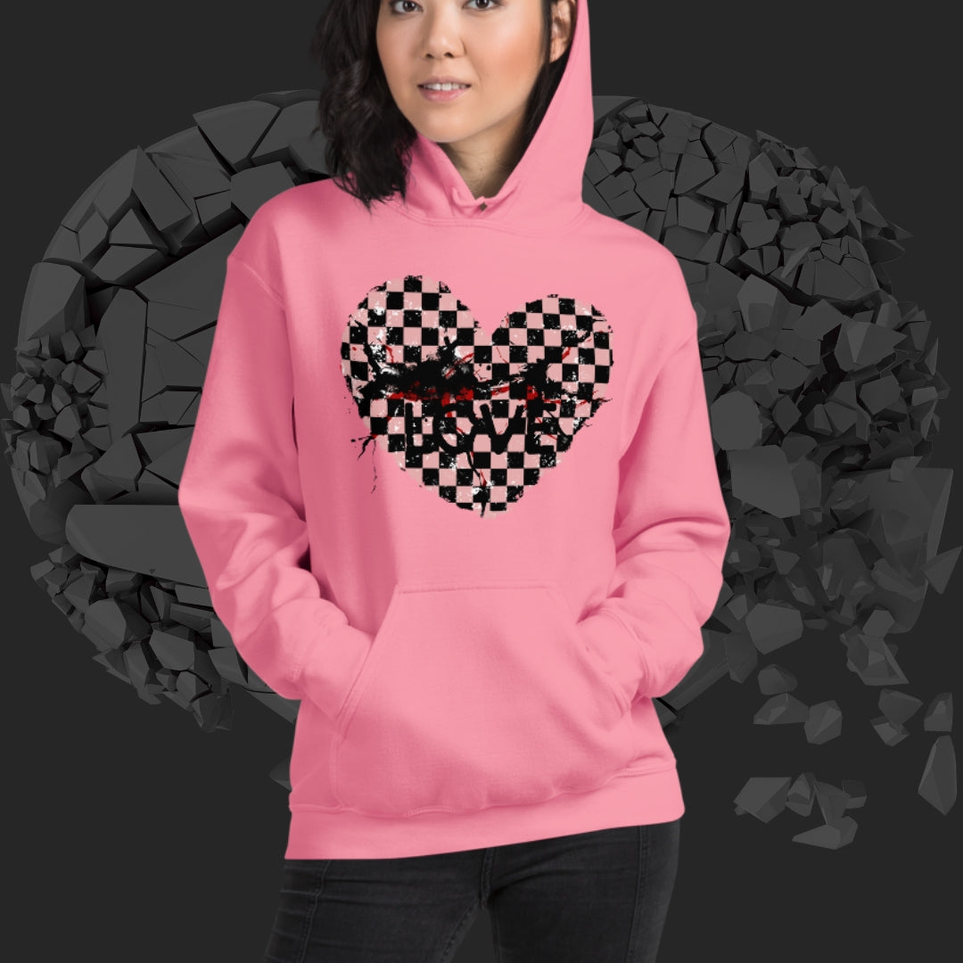 Person wearing a pink hoodie with a pink checkered and distressed heart design against a dark background
