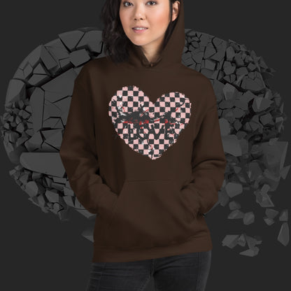 Person wearing a brown  hoodie with a pink checkered and distressed heart design against a dark background