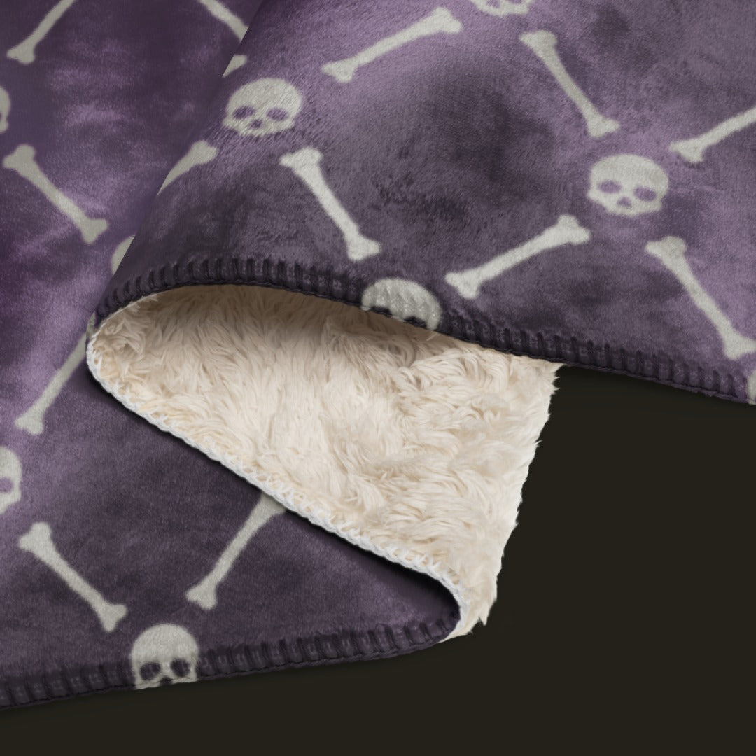 A fleece sherpa blanket with a soft argyle pattern and skulls and bones diagonals