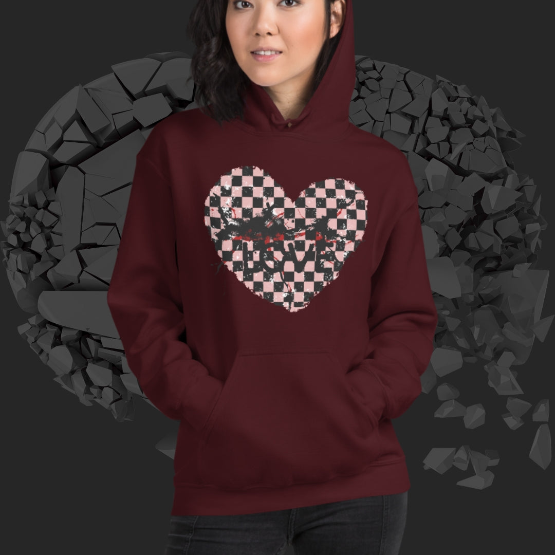 Person wearing a maroon hoodie with a pink checkered and distressed heart design against a dark background