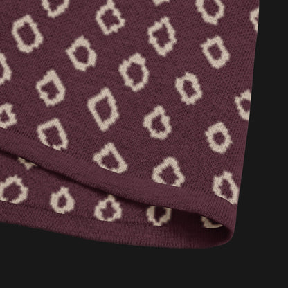 A burgundy short sleeve knit featuring a line art skull with headphones and hand drawn diamonds