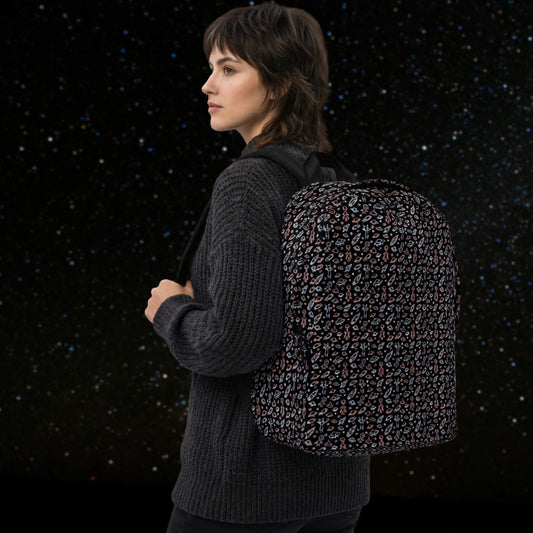 Woman wearing a backpack with a hand drawn space pattern featuring scattered confused aliens, planets, comets, and UFOs in pastel on black. 