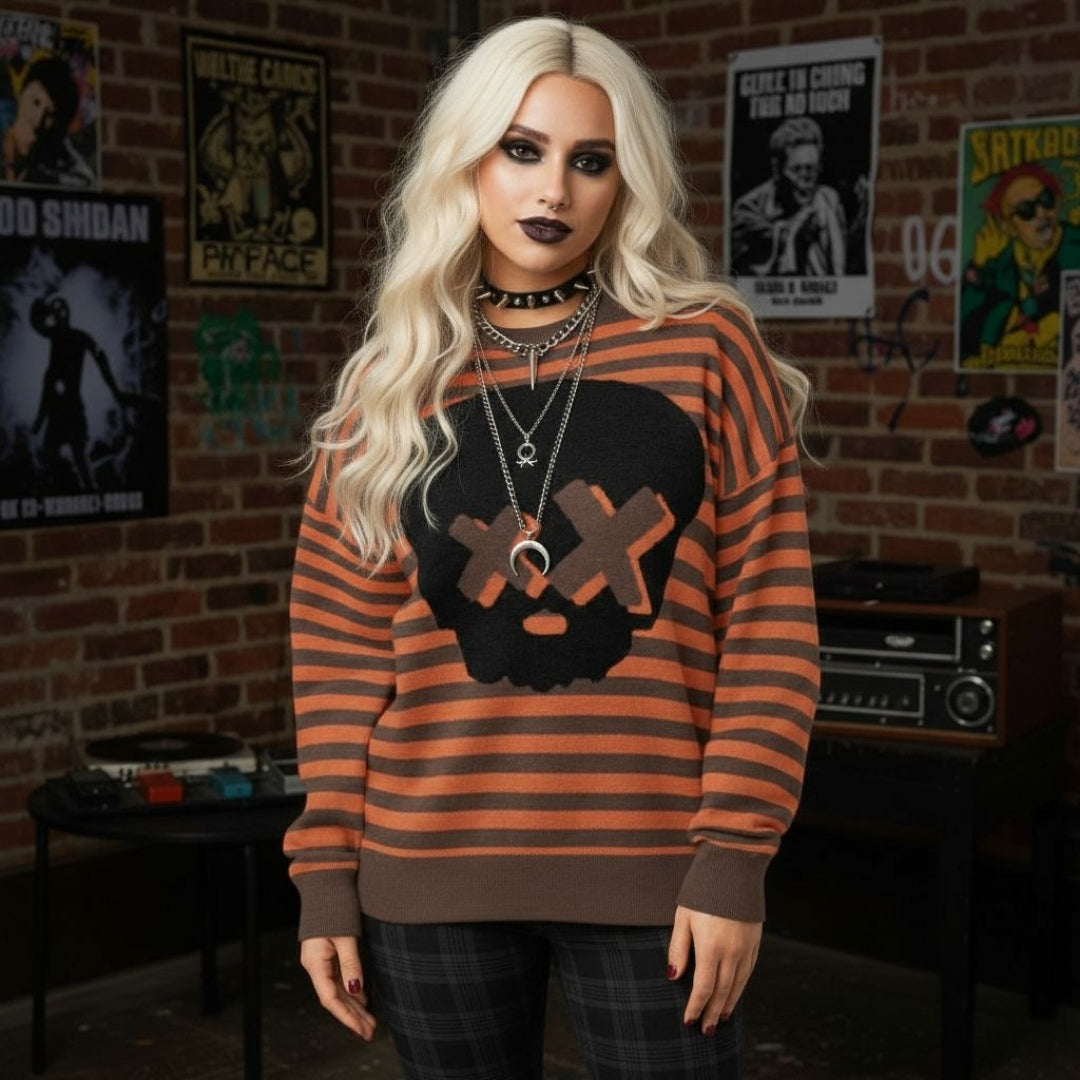 Alt style person wearing a brown-orange striped knitted sweater with a x-eye skull design in a room with posters on the wall.