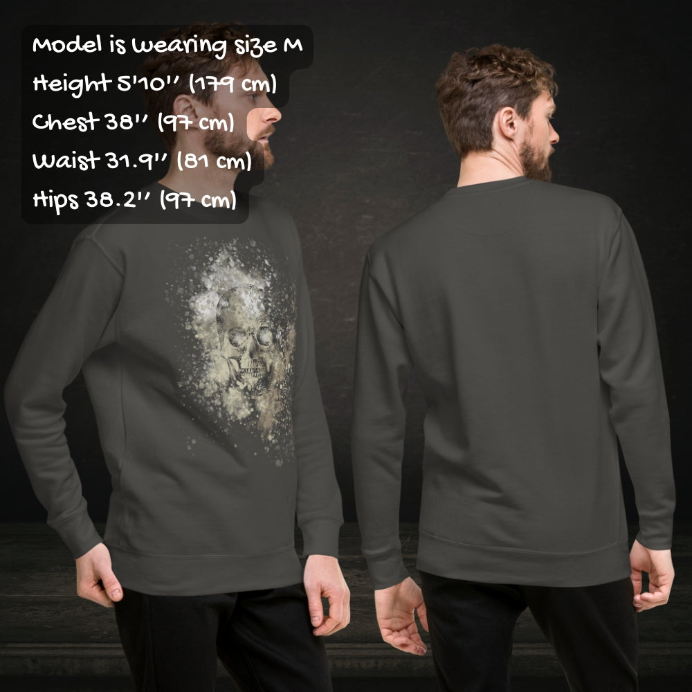Person wearing a cotton heritage M2480 sweatshirt with a subtle skull graphic surrounded and overlaid with paint splatter in camouflage colors with sizing info