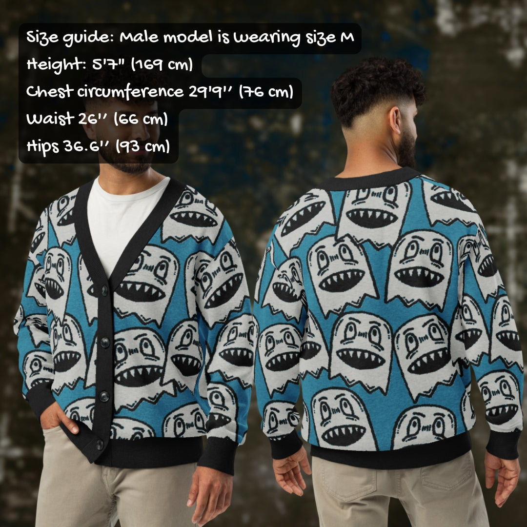 A man wearing an electric blue knitted cardigan with large grey grinning goblins and sizing info.