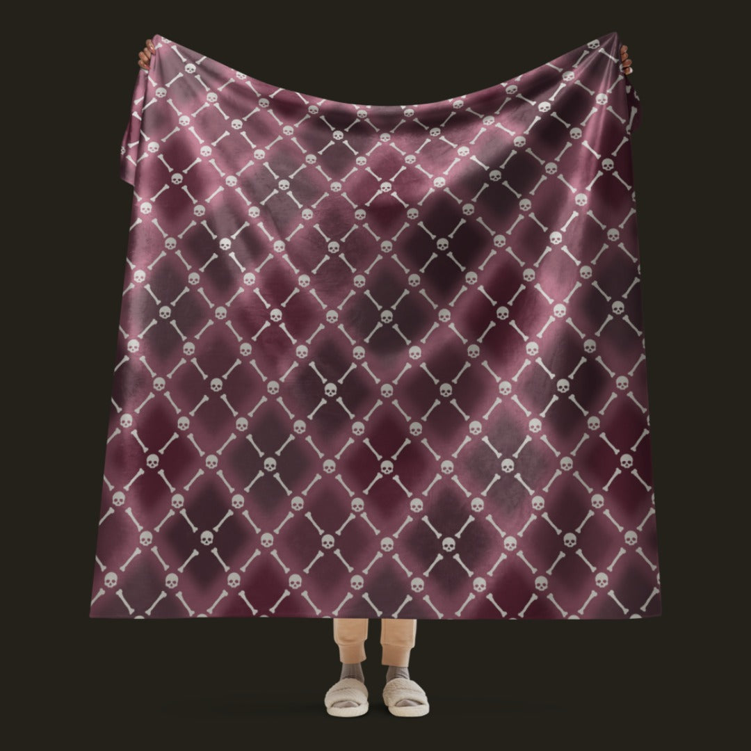 A fleece sherpa blanket with a soft argyle pattern and skulls and bones diagonals