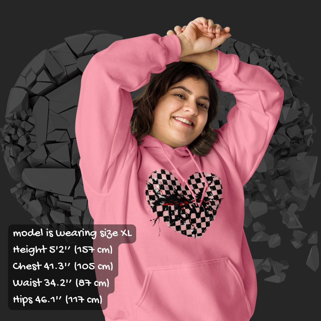 Person wearing a pink hoodie with a pink checkered and distressed heart design against a dark background