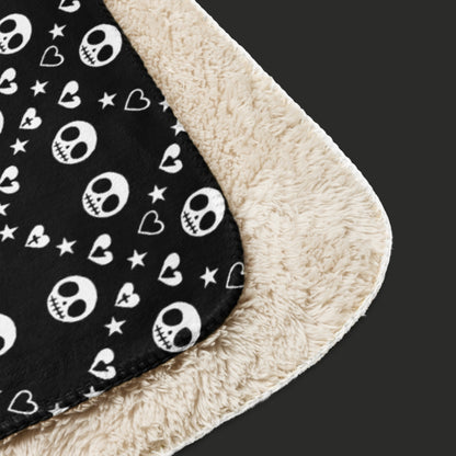 Black sherpa blanket with repeating white skull/ghoul, heart, and star geometric pattern, oversized emo aesthetic throw