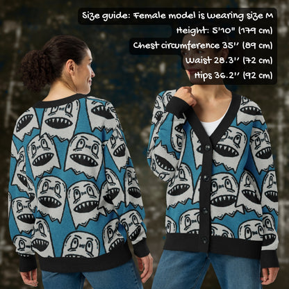 A woman wearing an electric blue knitted cardigan with large grey grinning goblins and sizing info.