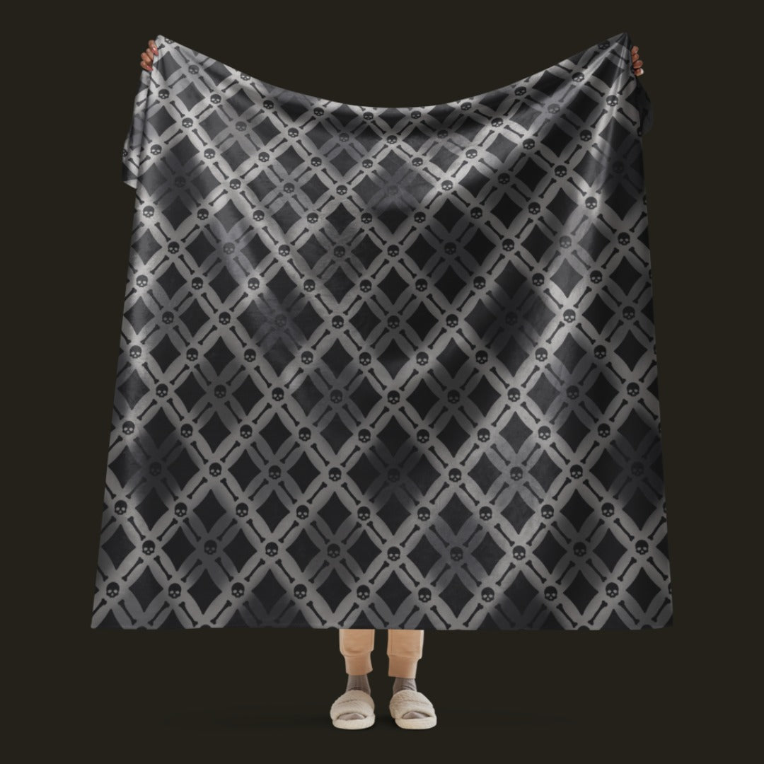 A fleece sherpa blanket with a soft argyle pattern and skulls and bones diagonals