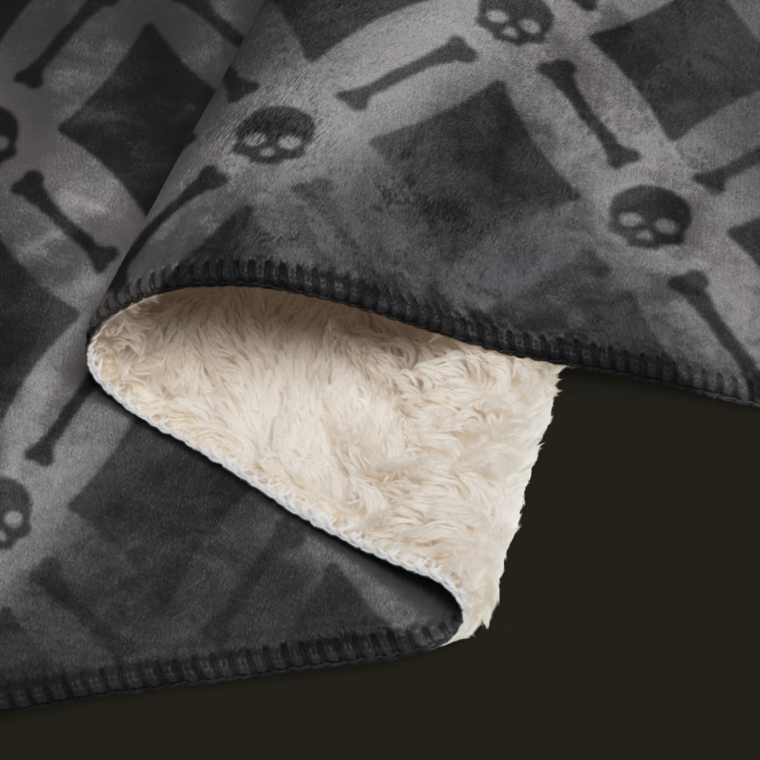 A fleece sherpa blanket with a soft argyle pattern and skulls and bones diagonals