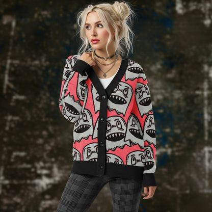 An alt style woman is wearing a hot pink knitted cardigan with large grey grinning goblins and dark plaid leggings.