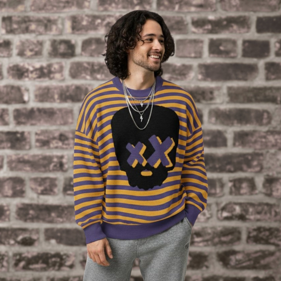 Alt style person wearing a violet-mustard striped knitted sweater with a x-eye skull design by a brick wall