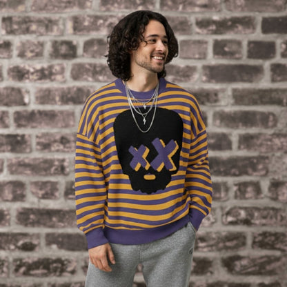 Alt style person wearing a violet-mustard striped knitted sweater with a x-eye skull design by a brick wall