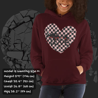 Person wearing a maroon hoodie with a pink checkered and distressed heart design against a dark background