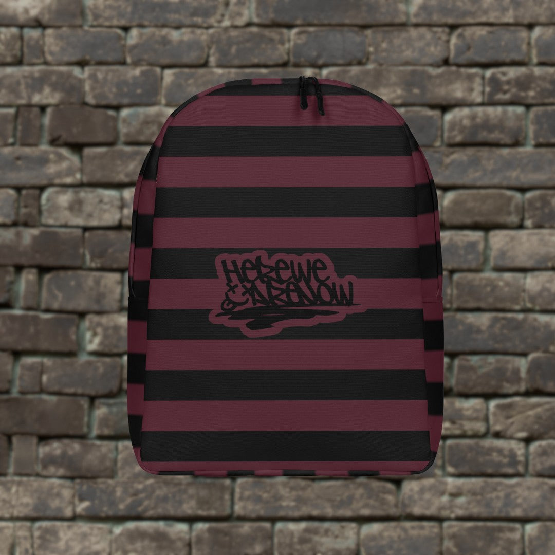 Backpack with burgundy and black grunge style dark stripes and text "here we are now" in graffiti tag style