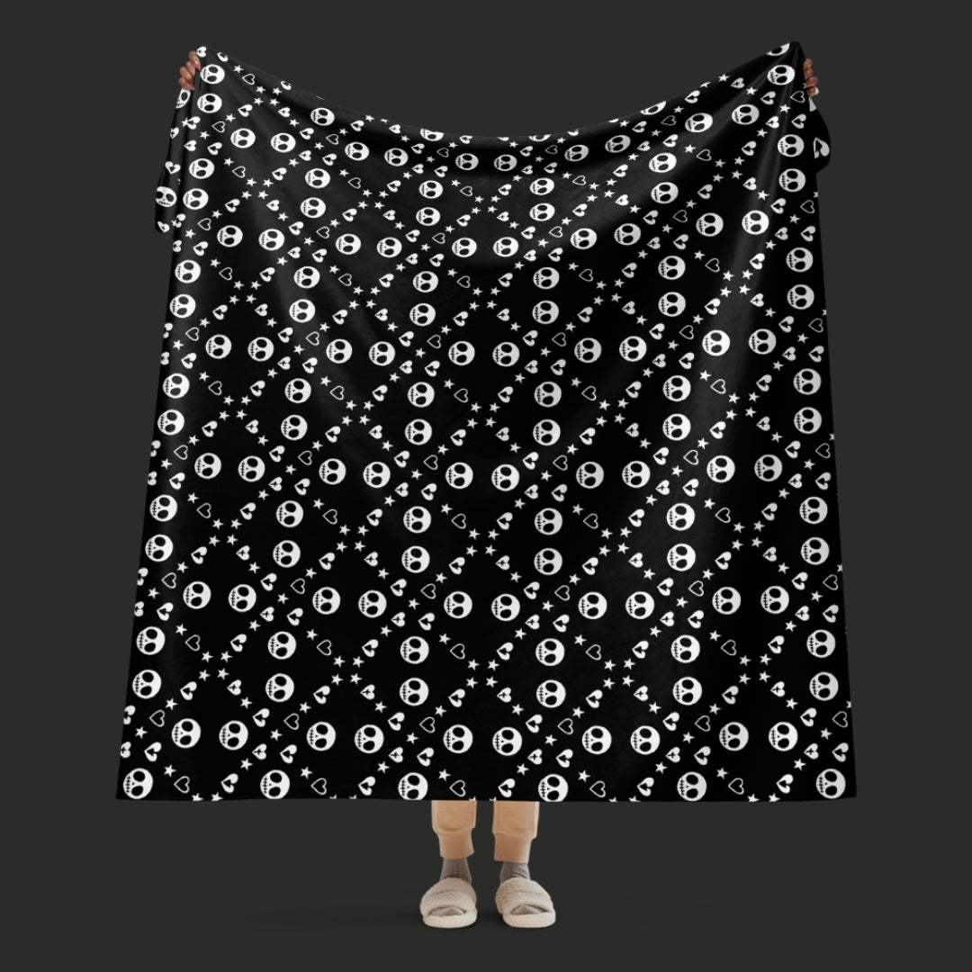 Black sherpa blanket with repeating white skull/ghoul, heart, and star geometric pattern, oversized emo aesthetic throw