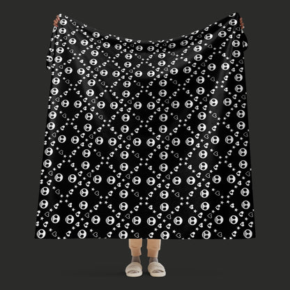 Black sherpa blanket with repeating white skull/ghoul, heart, and star geometric pattern, oversized emo aesthetic throw
