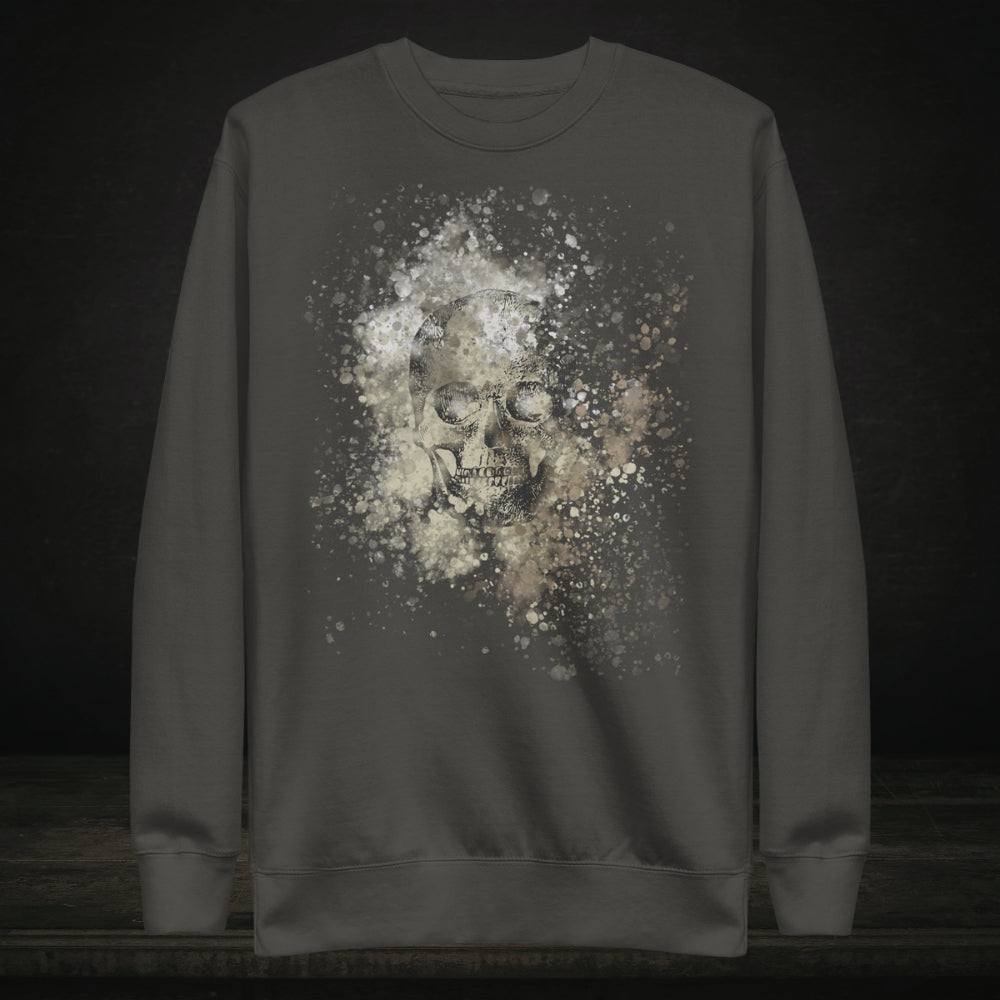 A cotton heritage M2480 sweatshirt with a subtle skull graphic surrounded and overlaid with paint splatter in camouflage colors on vintage black