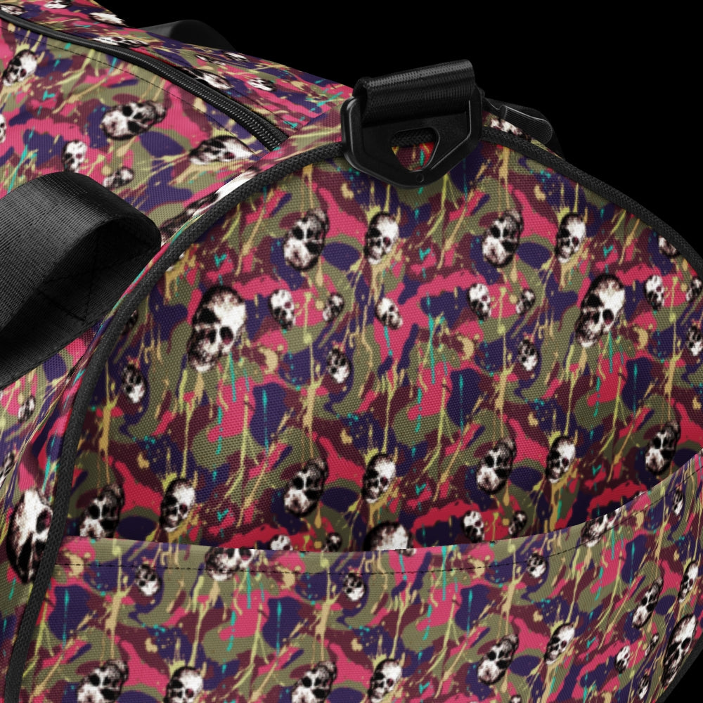 a duffel gym bag with a camo, paint splatter, and gritty skulls pattern in pink and purple shades