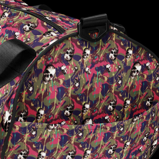 a duffel gym bag with a camo, paint splatter, and gritty skulls pattern in pink and purple shades