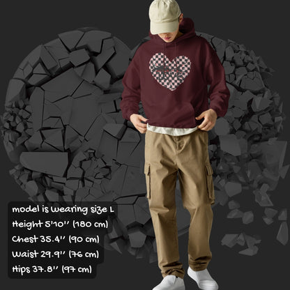 Person wearing a brown  hoodie with a pink checkered and distressed heart design against a dark background