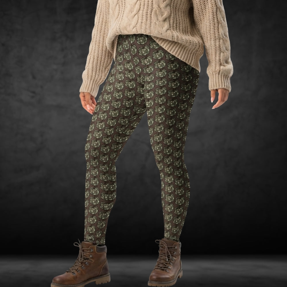 Person wearing leggings with camouflage colored pumpkins on brown background, together with a large knit and boots