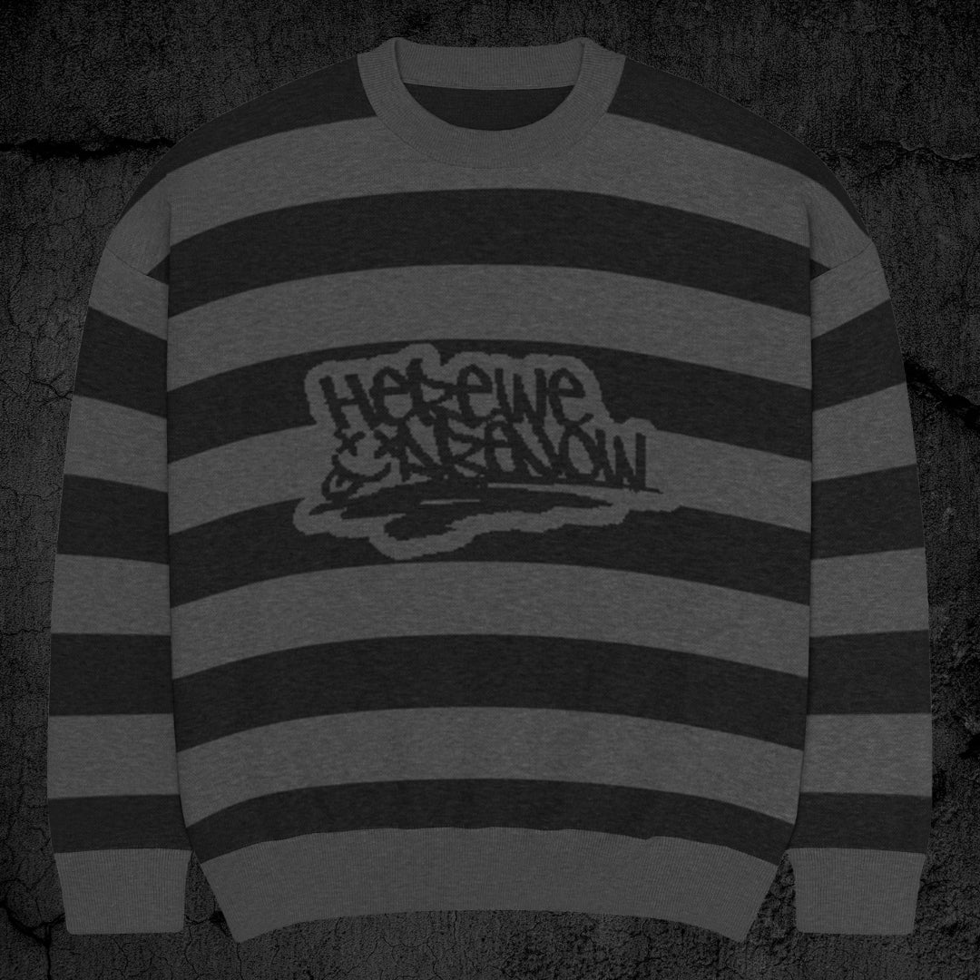 Black and grey grunge striped knitted sweater with a text "here we are now" in graffiti tag style, on a dark textured background