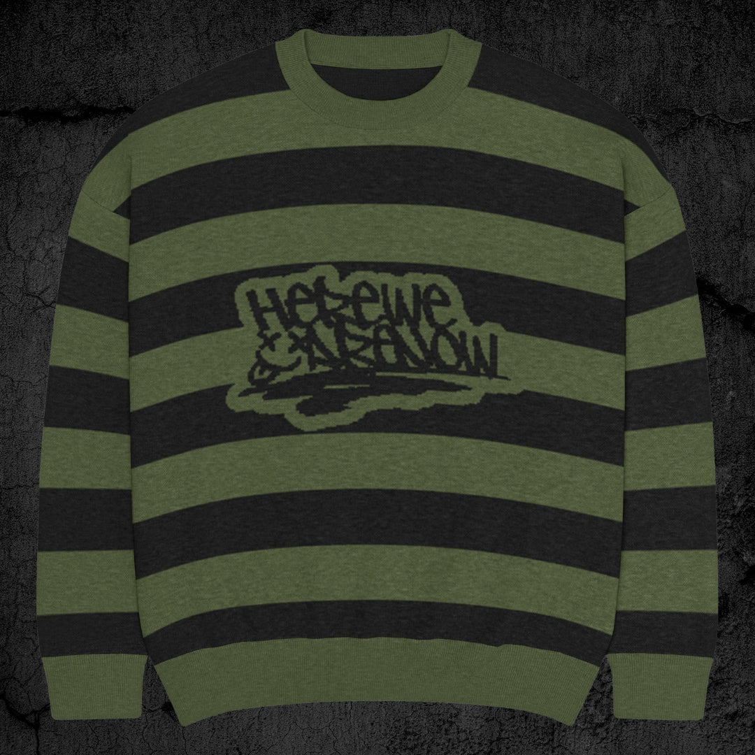 Black and green grunge striped knitted sweater with text "here we are now" in graffiti tag style, on a dark textured background