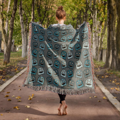 A woven blanket with grinning blue shade goblins on a grey background