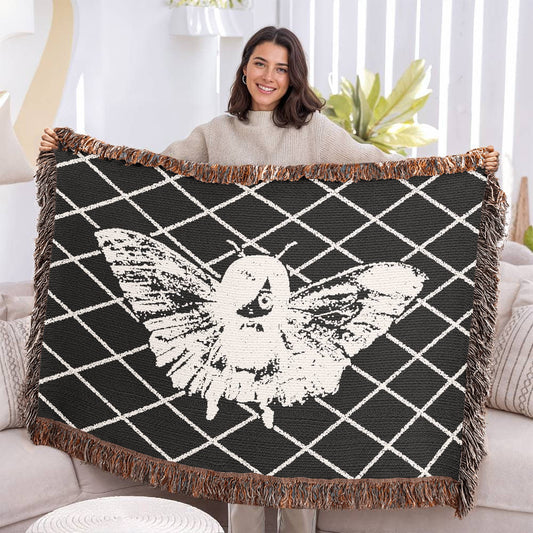 woman holding a woven blanket featuring a moth girl, wings spread on a background of a lattice grid