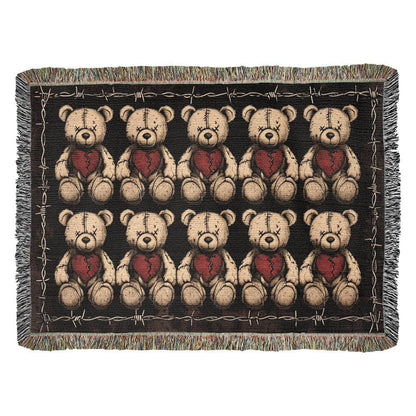 a woven blanket with x-eyed teddy bears on a dark background and surrounded by a frame of barbed wire