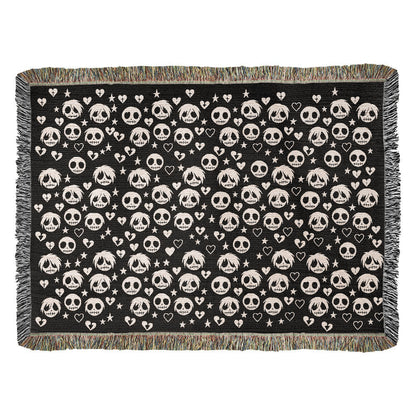 a woven blanket with a pattern of stitch mouthed emo ghouls and broken hearts on a dark background