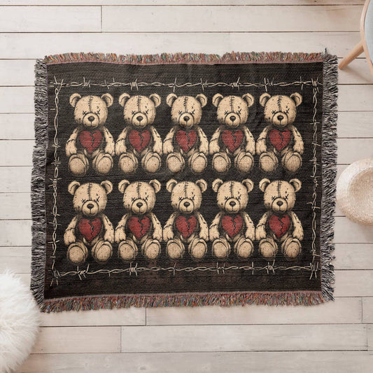 a woven blanket with x-eyed teddy bears on a dark background and surrounded by a frame of barbed wire
