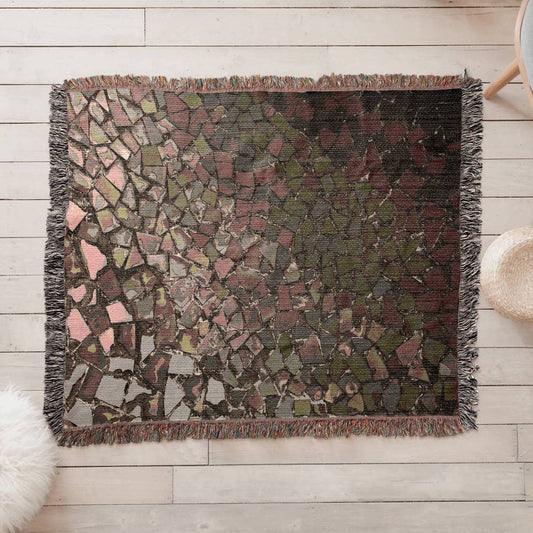 A woven blanket with deep red, black and lighter color shattered mosaic image